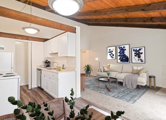 A living room with carpet floors and view into dining room and kitchen at Foster Creek apartments in Tukwila, WA