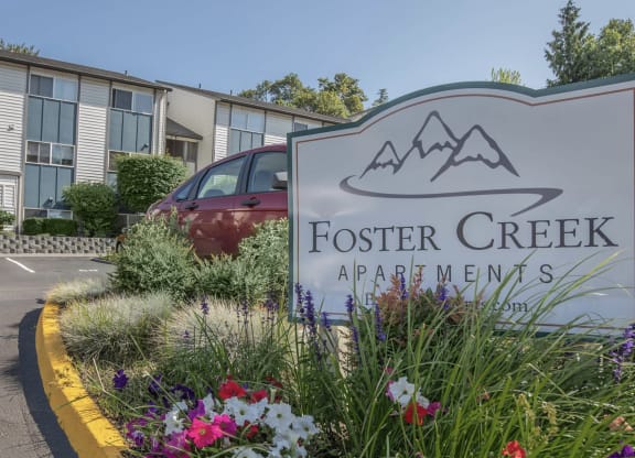 A sign for foster creek apartments with flowers in front of it