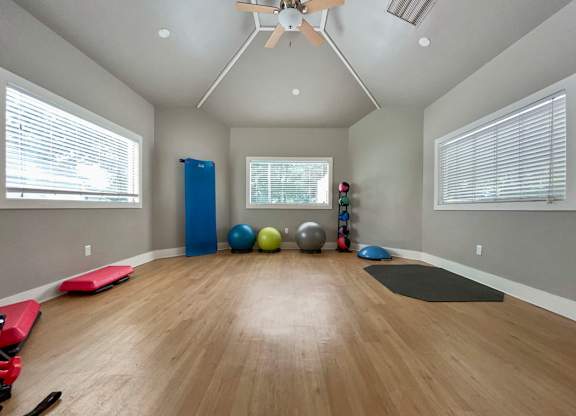 a yoga room with yoga mats and a ceiling fan