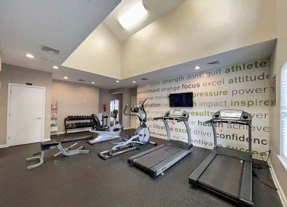 a gym with weights and a monitor on the wall