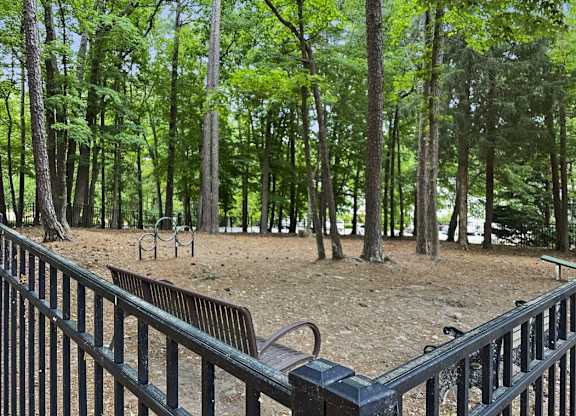 a park with benches and trees and a fence