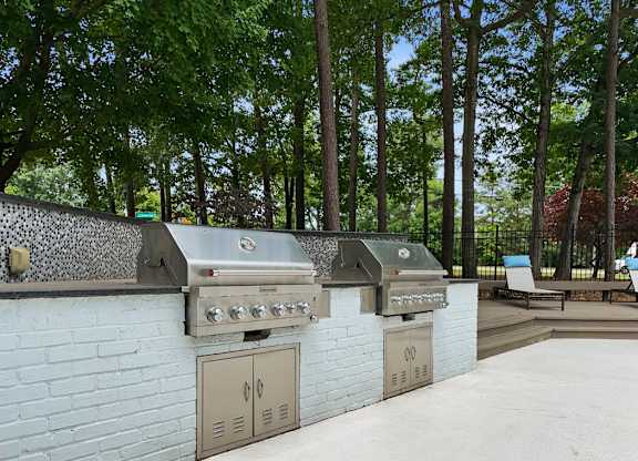 the outdoor kitchen has two grills and two refrigerators