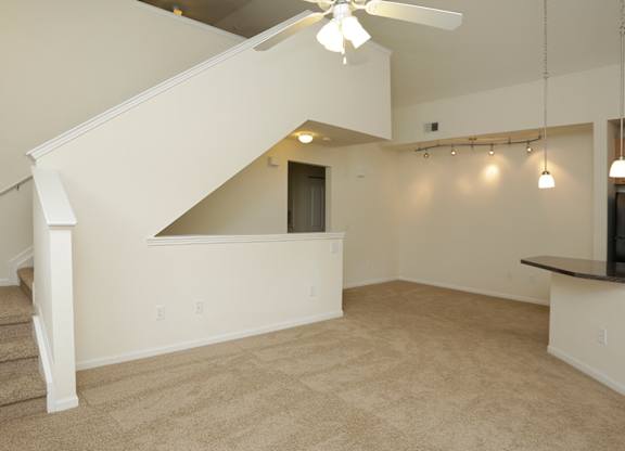 A room with a staircase and a ceiling fan.