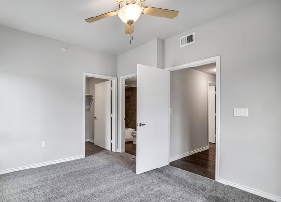 a bedroom with a ceiling fan and a door to a bathroom