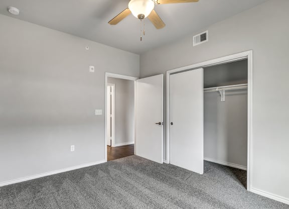 an empty bedroom with a ceiling fan and closet