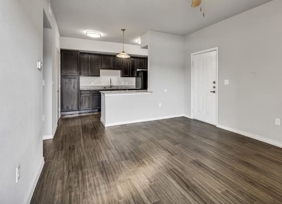 the living room and kitchen of an empty apartment with wood flooring