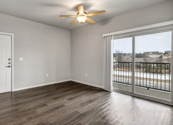 an empty living room with a balcony and a ceiling fan