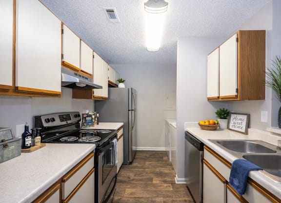 A kitchen with a stove, refrigerator, and sink.