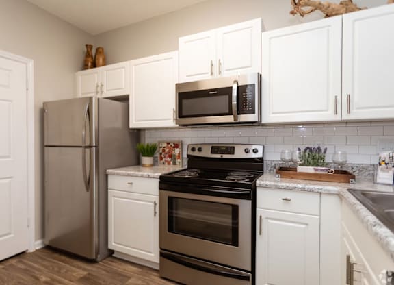 A kitchen with a stainless steel refrigerator, oven, and microwave.