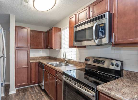 A kitchen with brown cabinets and a black stove top oven.