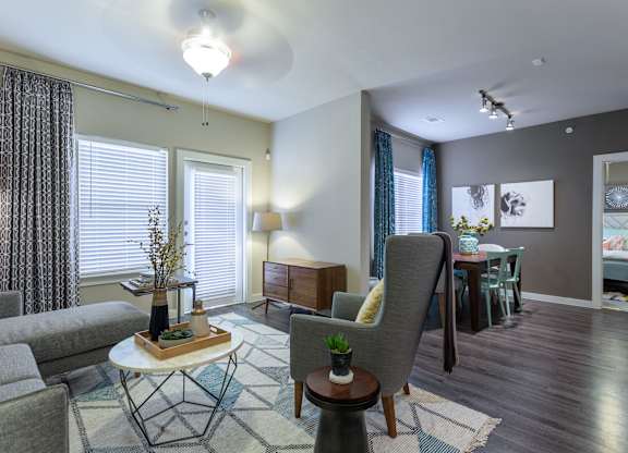 A living room with a grey couch, a white coffee table, and a grey armchair.