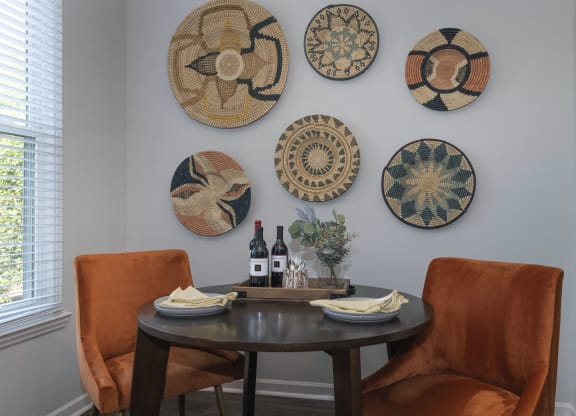 a dining area Seasons at Umstead apartments in Raleigh with a table and two orange chairs