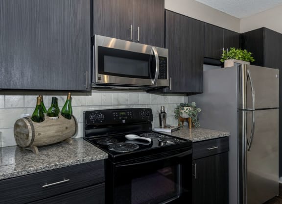 a kitchen with dark cabinets and stainless steel appliances