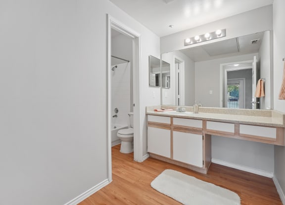 a bathroom with white walls and wood flooring