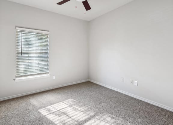 an empty room with a window and a ceiling fan