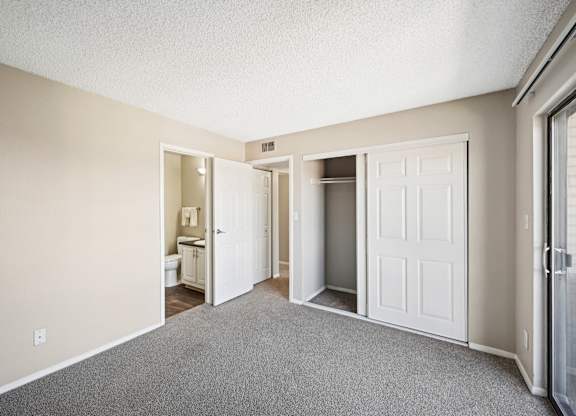an empty bedroom with a closet and carpet flooring