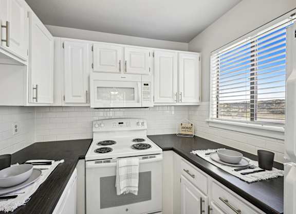 an empty kitchen with white cabinets and appliances