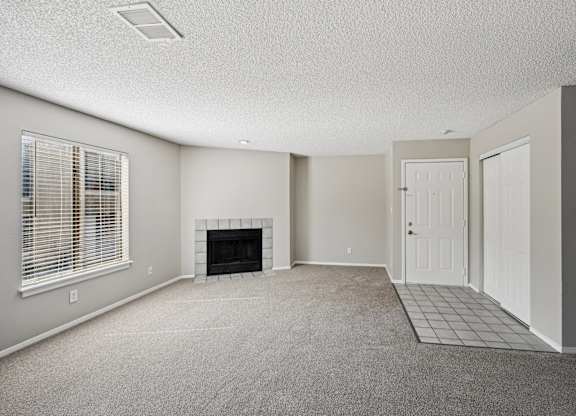 an empty living room with a fireplace and a white door