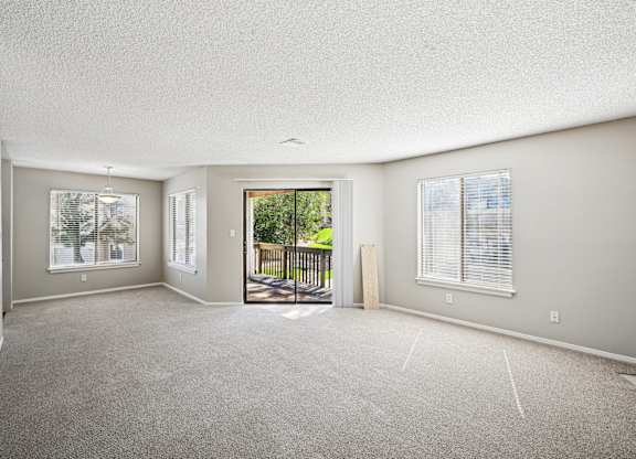 an empty living room with a door to a balcony