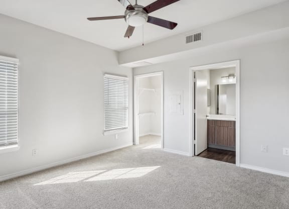 an empty living room with a ceiling fan and a door to a bathroom