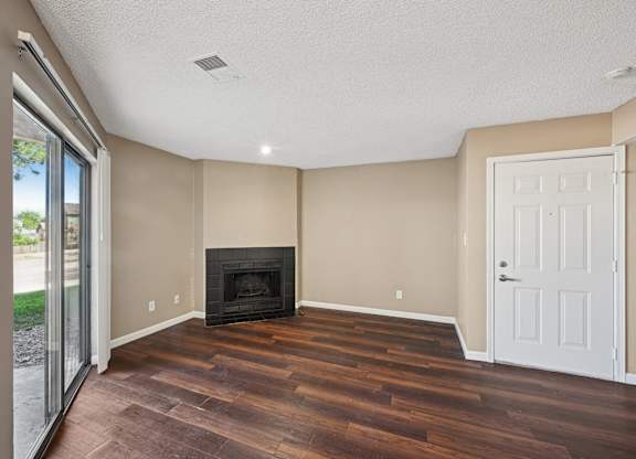 an empty living room with wood floors and a fireplace