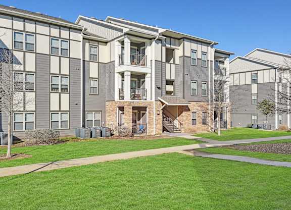 an exterior view of an apartment building with green grass and sidewalks