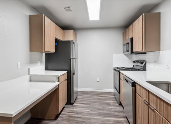 an empty kitchen with white countertops and a stainless steel refrigerator
