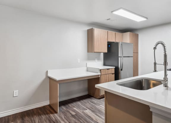 an empty kitchen with white countertops and a stainless steel refrigerator