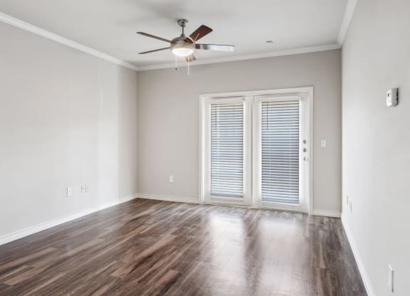 an empty living room with wood floors and a ceiling fan