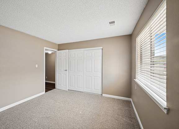an empty living room with a large window and a white door
