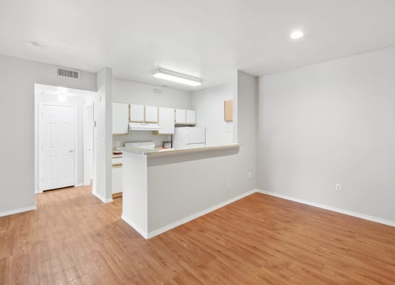 a bedroom with a medium hardwood floor and a kitchen in the background