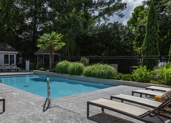 a swimming pool with lounge chairs and a gazebo in the background at Eclipse Apartments in Duluth