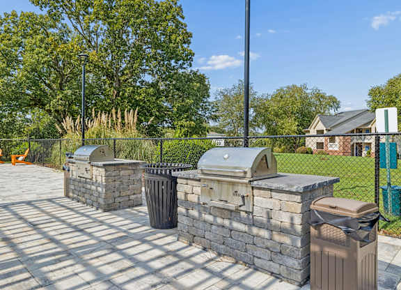 A row of stone trash cans are lined up on a sidewalk.