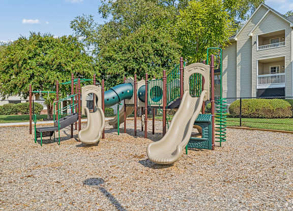 A playground with a green slide and a red and green play structure.