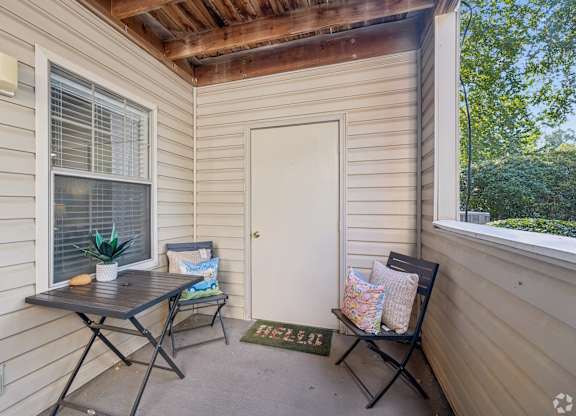 A small balcony with a table and chairs.