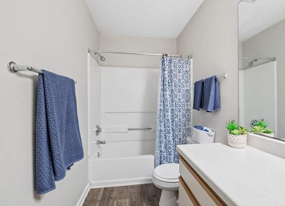 A small bathroom with a toilet, sink, and shower.