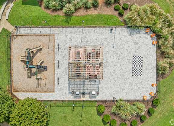 A playground with a slide, swings, and a checkered pattern on the ground.