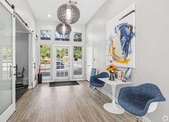 A modern room with a white table and blue chairs.
