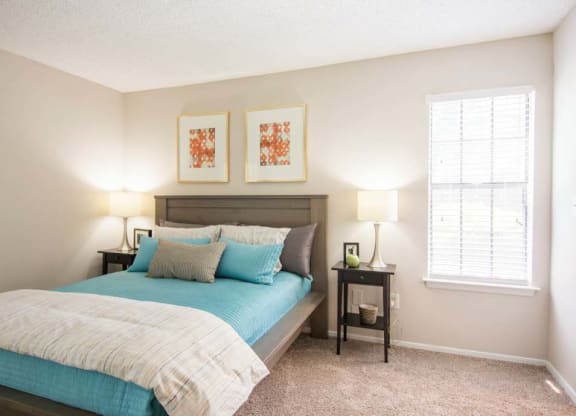 a bedroom with a bed and two lamps and a window
