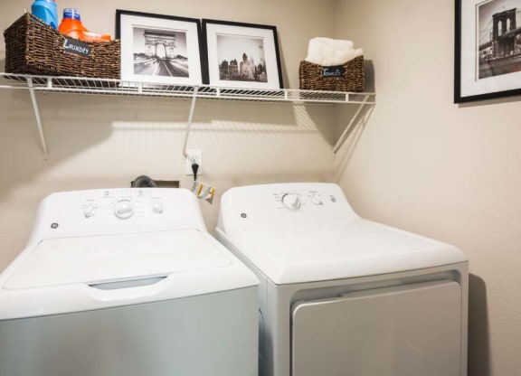 a washer and dryer in a laundry room with pictures on the wall
