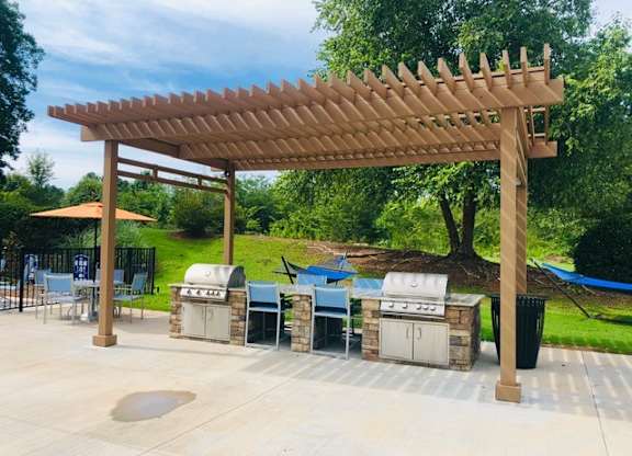 A wooden pergola is over a table and chairs.