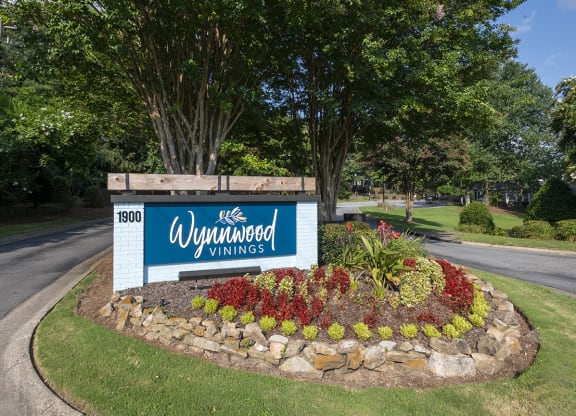 a sign for Wynnwood Vinings apartments on a roundabout with a flower garden