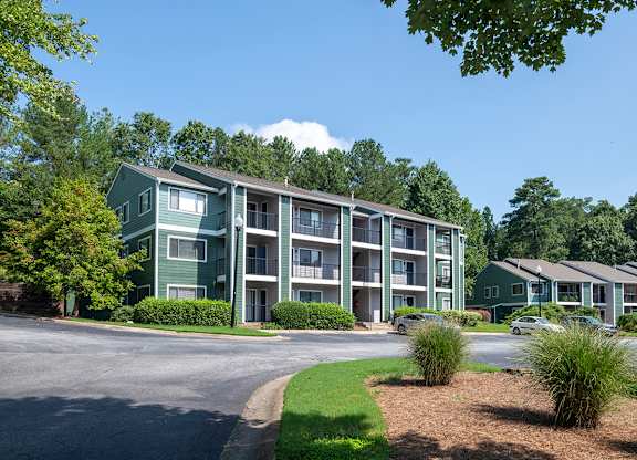 Apartment complex with green trees and a clear blue sky.