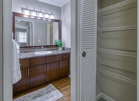 A bathroom with a large mirror, sink, and wooden cabinets.