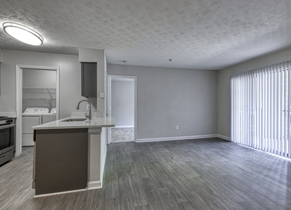 an empty living room and kitchen with a large window