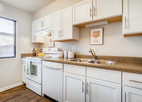 A kitchen with white appliances and cabinets at The Ranch at Bear Creek Apartments, Lakewood, CO, 80227