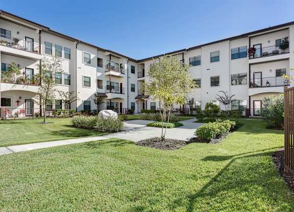 Apartment complex with tree in the front yard at The Laurel at Vintage Park 55+ Apartments, Tomball Texas