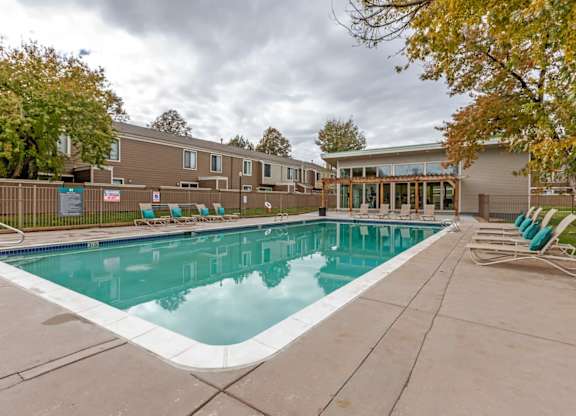 A swimming pool surrounded by a concrete floor and a wooden fence at The Ranch at Bear Creek Apartments, Lakewood
