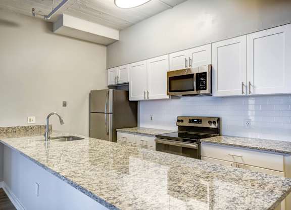 A kitchen with granite countertops and white cabinets.at 222 Saratoga, Maryland, 21202