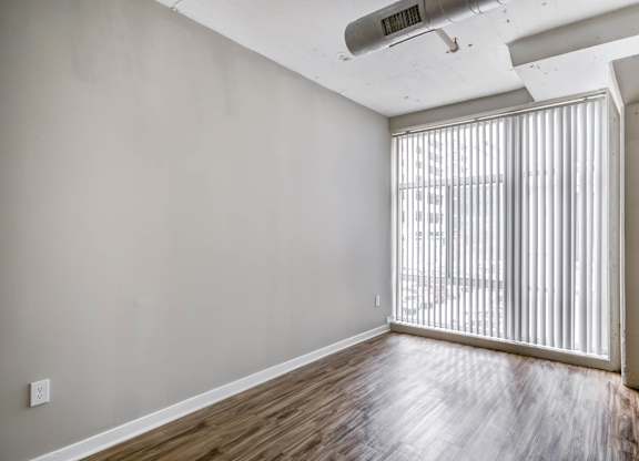 A room with wooden flooring and a window with blinds.at 222 Saratoga, Baltimore, MD